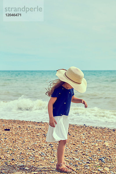 Junges Mädchen  das am Strand steht und Muscheln sucht