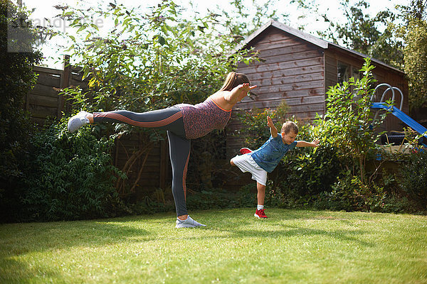 Mutter und Sohn üben im Garten  stehend in Yogastellung