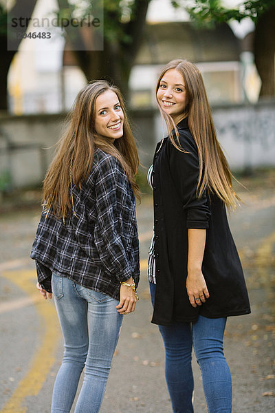 Porträt von zwei jungen Freundinnen  die sich im Park über die Schulter schauen