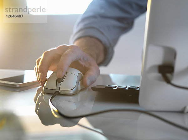 Die Hand eines Geschäftsmannes auf einer Computermaus bei der Arbeit im Büro