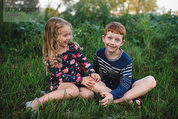 Mädchen und Bruder auf dem Feld sitzend