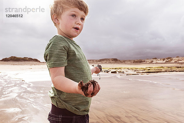 Junge am Strand mit nassem Sand in der Hand  Santa Cruz de Tenerife  Kanarische Inseln  Spanien  Europa