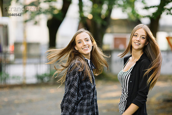 Porträt von zwei jungen Freundinnen mit langen braunen Haaren im Park