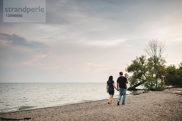Rückansicht eines Paares  das mit seinem Kleinkind am Strand spazieren geht  Ontariosee  Kanada