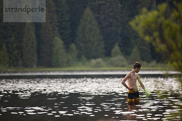 Teenager  im See fischend  mit Netz