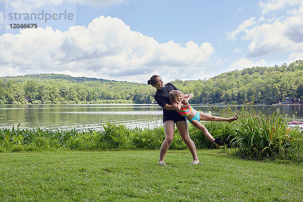 Mädchen schaukelt junges Mädchen auf Gras  am See