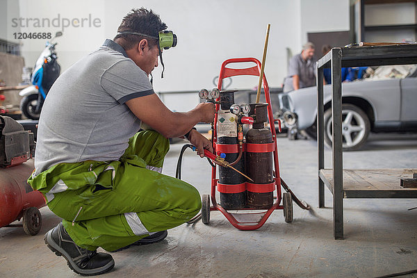 Mann bereitet Schweißvorrichtung in Karosserie-Reparaturwerkstatt vor