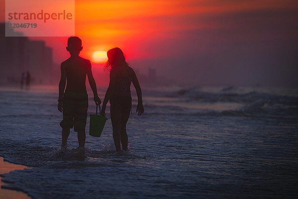 Geschwister paddeln im Meer bei Sonnenuntergang  North Myrtle Beach  South Carolina  Vereinigte Staaten