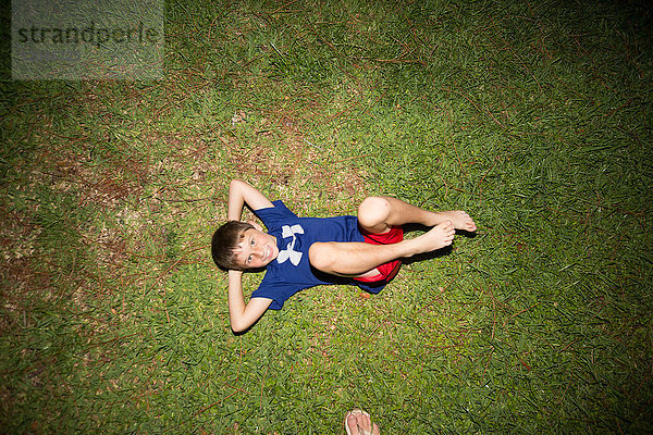 Junge auf dem Rücken auf Gras liegend  Blick von oben