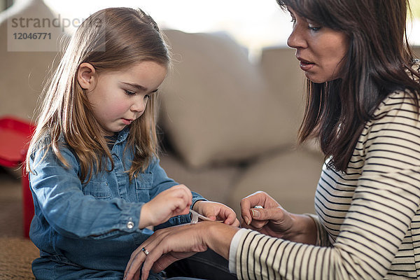 Mädchen klebt Pflaster auf die Hand der Mutter