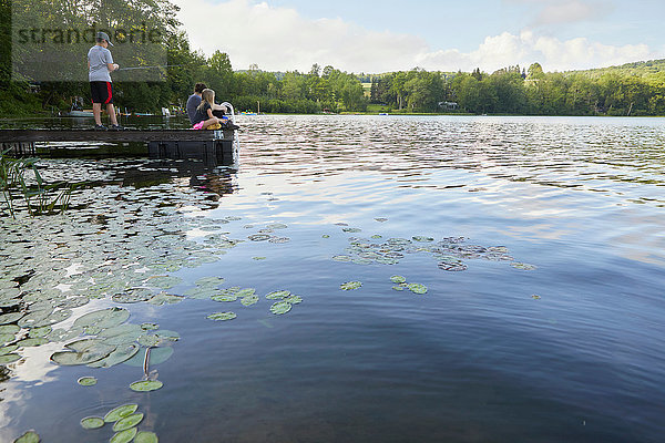 Drei Kinder auf Anlegesteg am See  kleiner Junge beim Angeln mit Angelrute