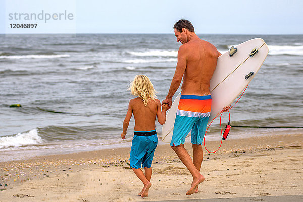 Erwachsener männlicher Surfer und Sohn auf dem Weg zum Meer  Asbury Park  New Jersey  USA