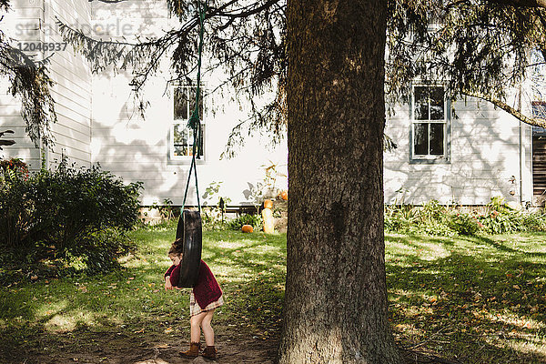 Mädchen auf Reifenschaukel am Baum hängend