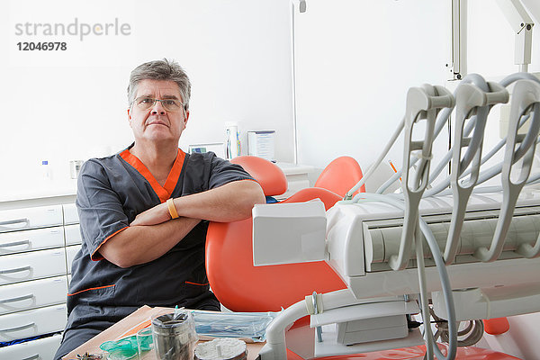 Zahnarzt am Behandlungsstuhl sitzend