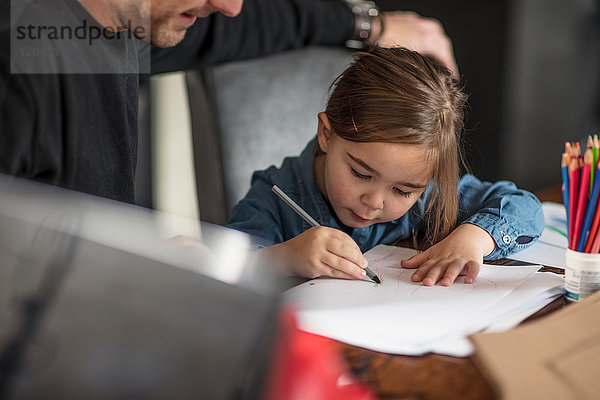 Junger Mann und seine Tochter beim Zeichnen am Tisch