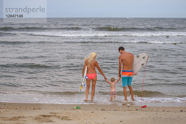 Rückansicht eines Surferpaares am Wasser mit Kleinkind-Tochter  Asbury Park  New Jersey  USA