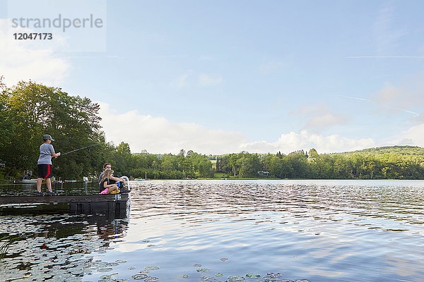 Drei Kinder auf Anlegesteg am See  kleiner Junge beim Angeln mit Angelrute