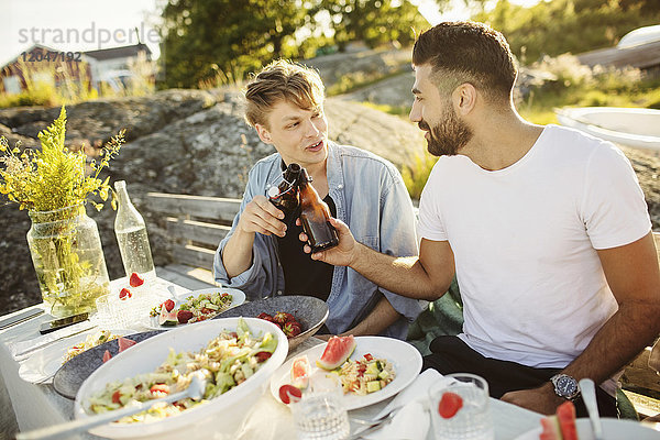 Freunde beim Trinken von Bierflaschen während des Mittagessens auf der Party