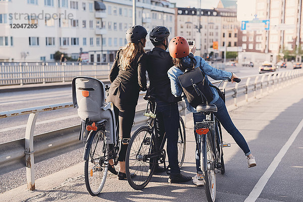 Rückansicht eines Mannes  der Selfie mit weiblichen Freunden mit Fahrrädern auf der Straße nimmt.
