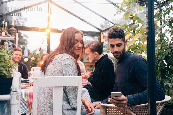 Low-Winkel-Ansicht von jungen Freunden mit smart während der Dinner-Party