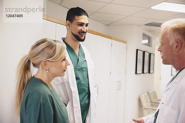 Reife Ärztin im Gespräch mit Kollegen im Krankenhauskorridor