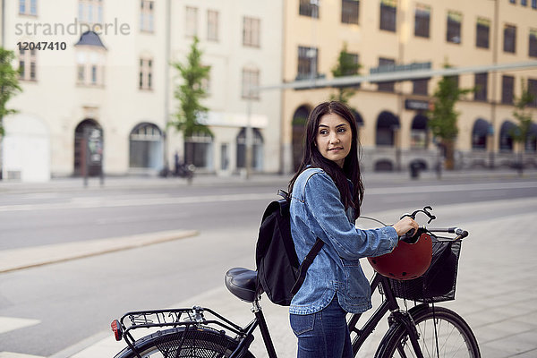 Mittlere erwachsene Frau schaut weg  während sie mit dem Fahrrad in der Stadt spazieren geht.