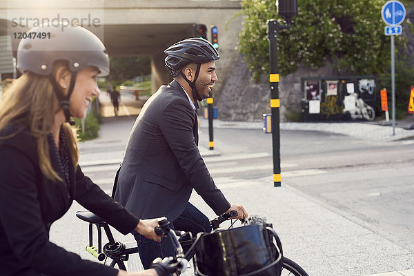 Seitenansicht der lächelnden Geschäftsleute beim Radfahren in der Stadt