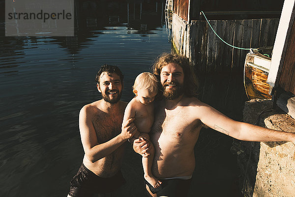 Lächelnder Vater mit Tochter im Stehen mit Freund am Seeufer