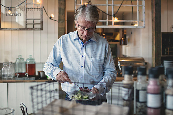 Senior Mann beim Essen im Teller an der Buffettheke