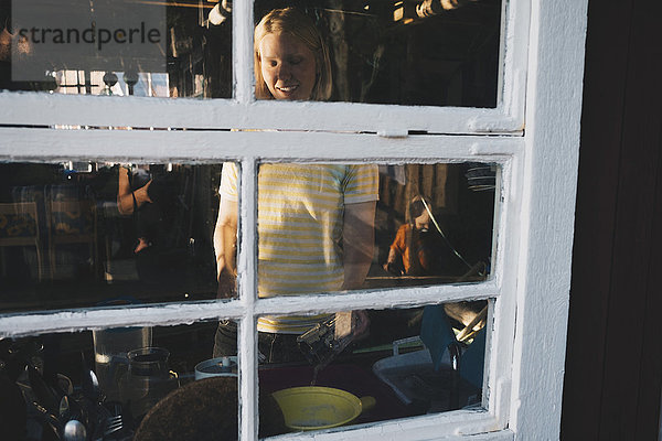 Lächelnde Frau beim Kochen vom Glasfenster aus gesehen
