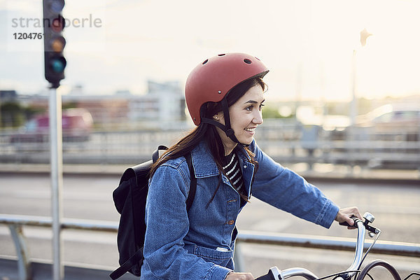 Lächelnde mittlere erwachsene Frau beim Radfahren in der Stadt