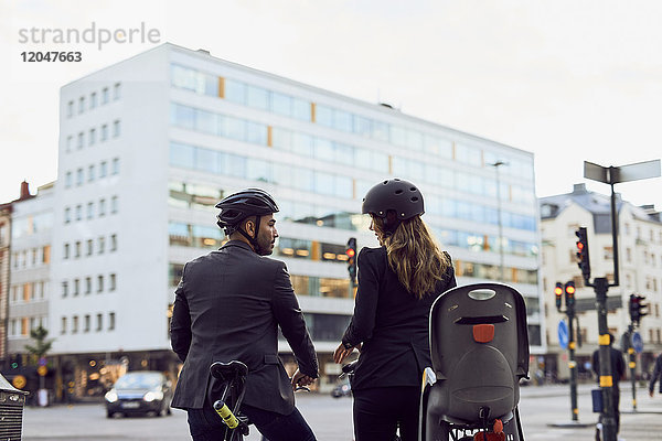 Rückansicht von Geschäftspartnern mit Fahrrädern auf der Straße in der Stadt