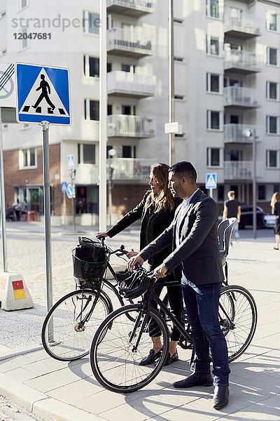Geschäftsleute stehen mit Fahrrädern auf dem Bürgersteig in der Stadt