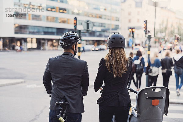 Rückansicht von Geschäftskollegen mit Fahrrädern auf der Straße in der Stadt