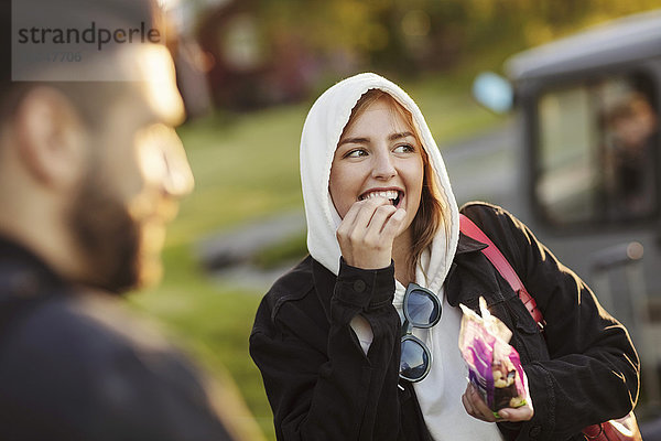 Fröhliche junge Frau  die von einem Mann isst  während sie wegguckt.