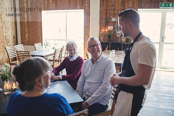 Junger Kellner nimmt Bestellung von Senioren im Restaurant entgegen