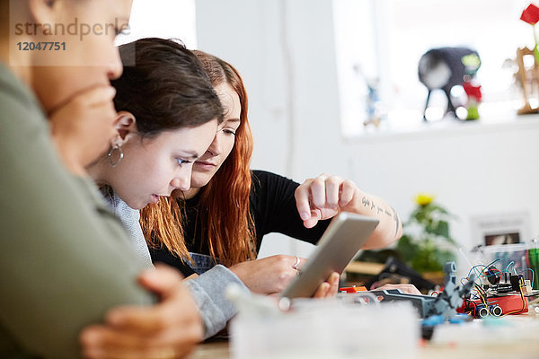 Multiethnische Ingenieurinnen mit digitalem Tablett am Tisch in der Werkstatt