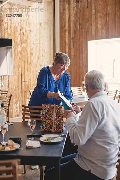 Seniorenfrau schenkt Freundin am Tisch im Restaurant während der Mittagsfeier