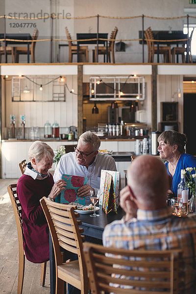 Fröhliches Seniorenpaar beim Mittagessen mit Freunden im Restaurant