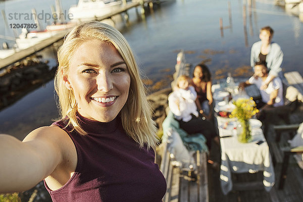 Porträt einer lächelnden jungen Frau mit Freunden im Hintergrund am Steg