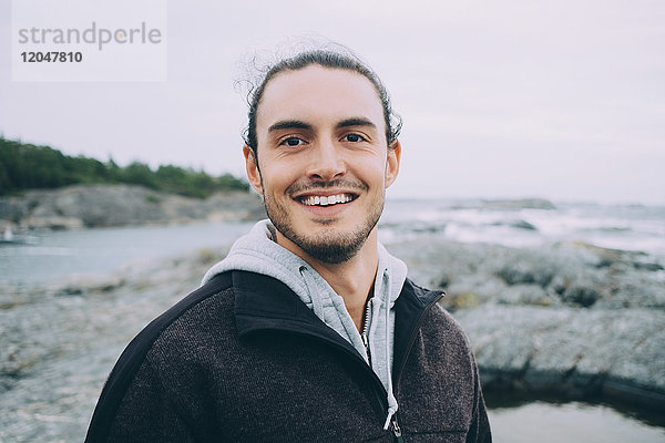 Porträt eines jungen Mannes  der am Strand lächelt
