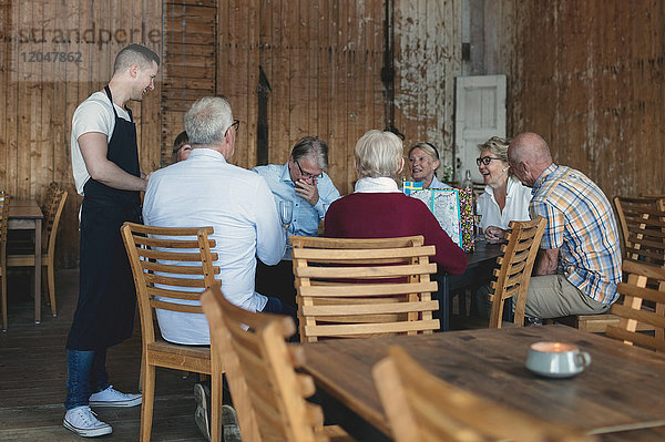 Junger Kellner nimmt Bestellung von Senioren im Restaurant entgegen