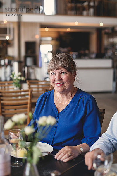 Porträt einer lächelnden Seniorin beim Mittagessen und Geselligkeit im Restaurant