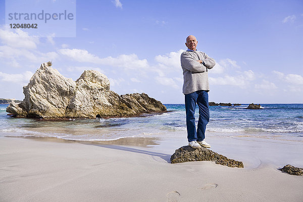 Ein Mann steht auf einem Felsen am Meer