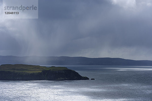 Sonnenbeschienene Meeresklippen und Regenwolken entlang der Küste der Isle of Skye in Schottland  Vereinigtes Königreich