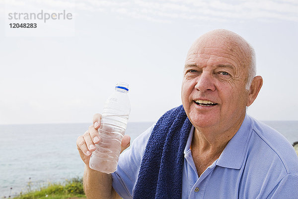 Porträt eines Mannes mit Handtuch um die Schultern  der eine Flasche Wasser trinkt