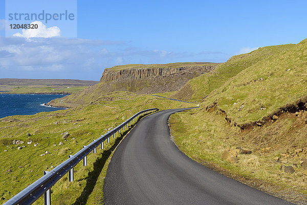 Typische schottische Landschaft auf der Isle of Sky mit einer Küstenstraße und Meeresklippen an einem sonnigen Tag in Schottland  Vereinigtes Königreich