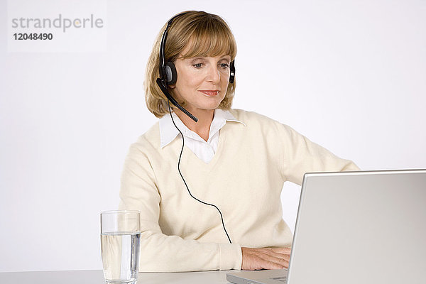 Frau mit Headset und Laptop-Computer