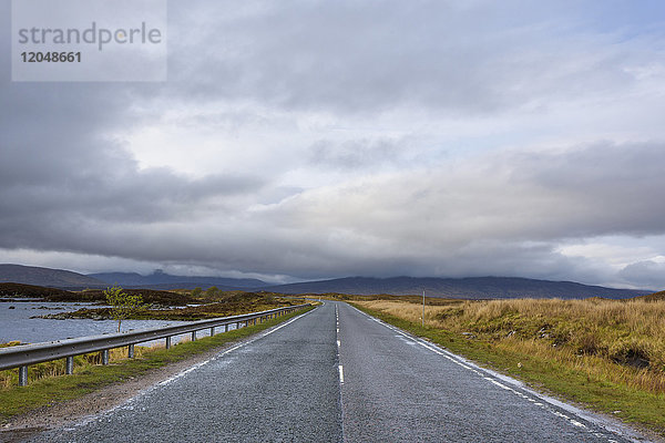 Landstraße durch Moorlandschaft mit dichtem Wolkenhimmel im Rannoch Moor in Schottland  Vereinigtes Königreich