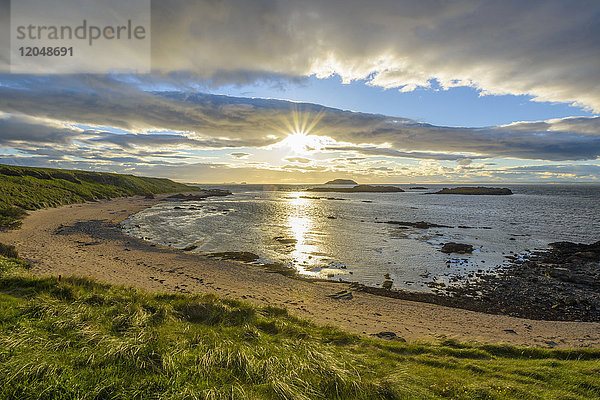 Sonnenschein über einer Bucht mit Sandstrand bei Sonnenuntergang in North Berwick am Firth of Forth in Schottland  Vereinigtes Königreich